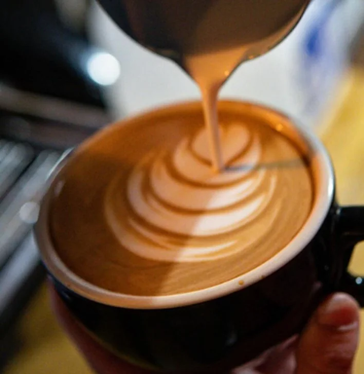 Leche vertida sobre un latte en taza negra