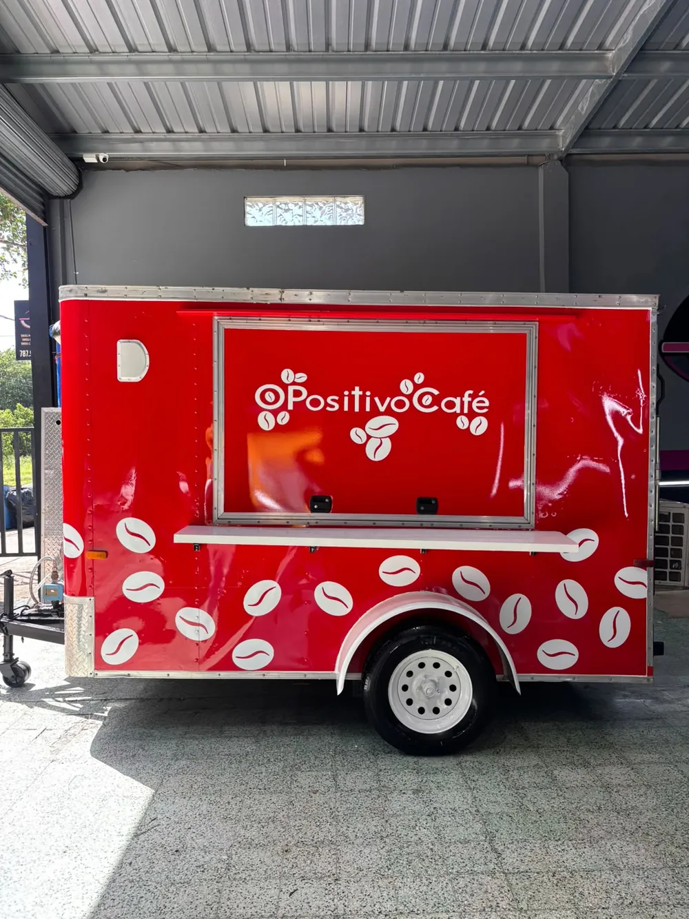 El carretón de O Positivo Café: rojo, con la ventanilla de servicio, el logo blanco y granos de café blancos