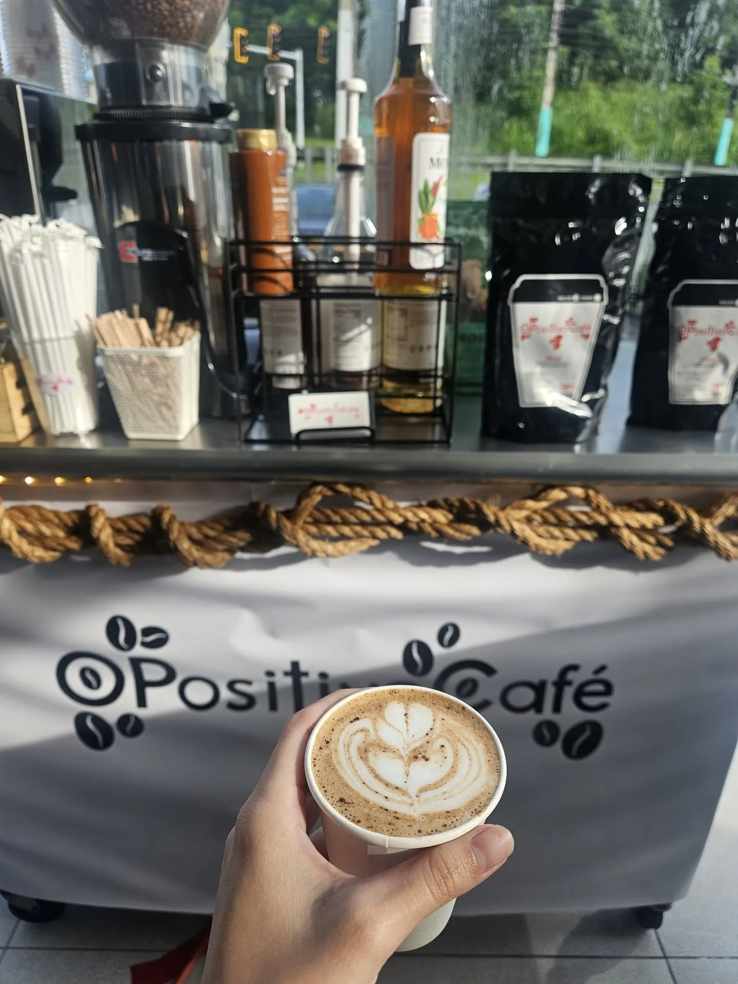 Un latte de O Positivo frente al carrito de café en una actividad